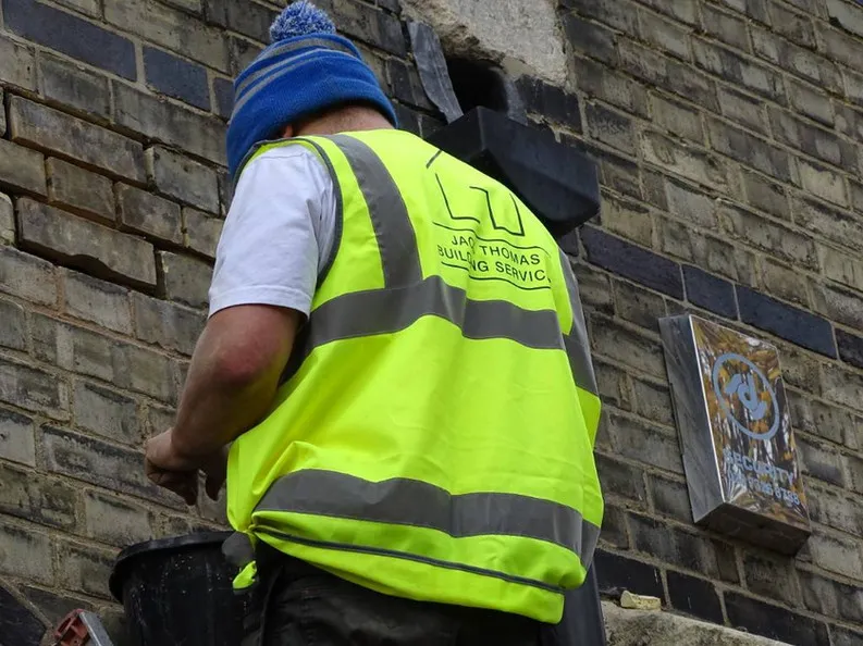 a man wearing a safety vest and a blue hat