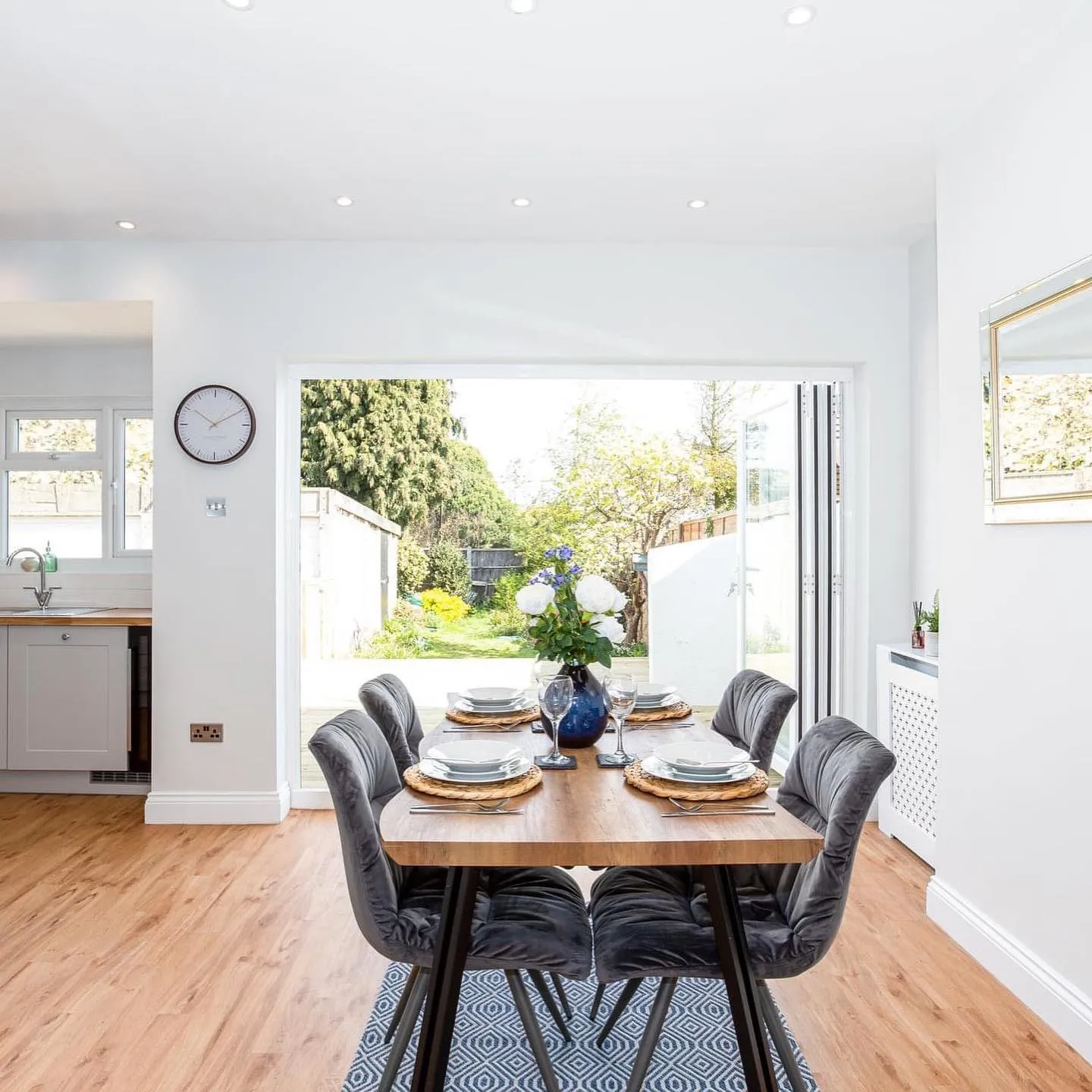 A dining room table with a clock on the wall.