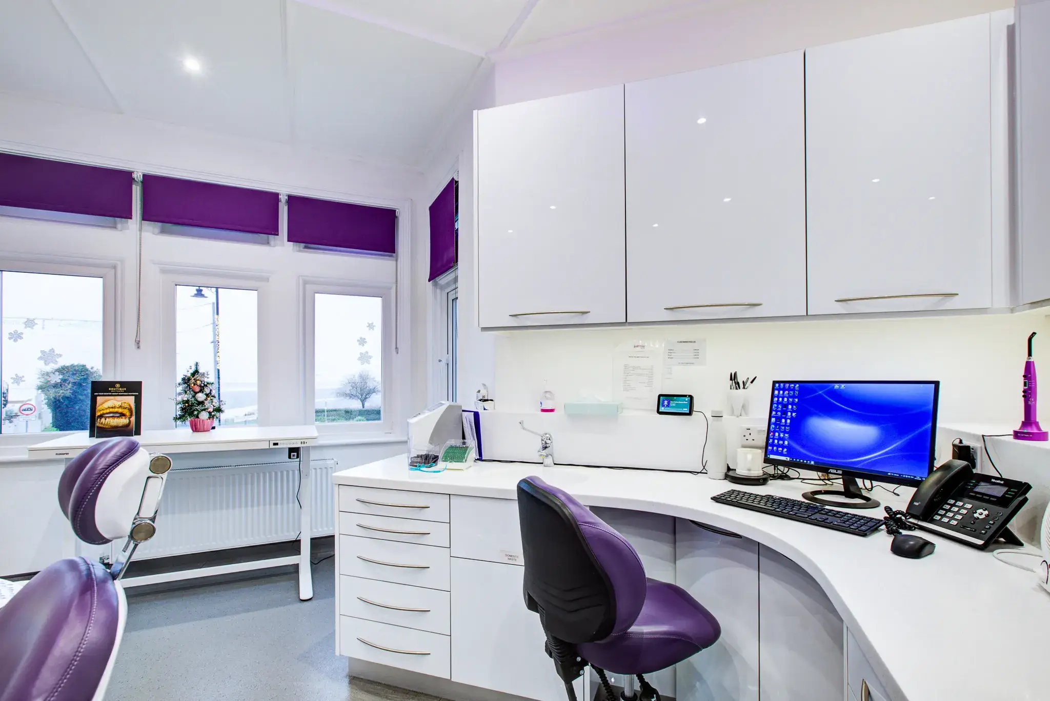 A white desk with a purple chair in a room.